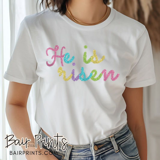 He is Risen in rainbow colors on a t-shirt